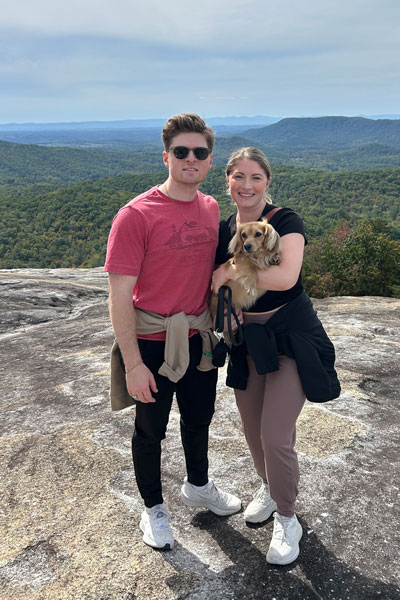 Christian with his wife and dog on top of mountain
